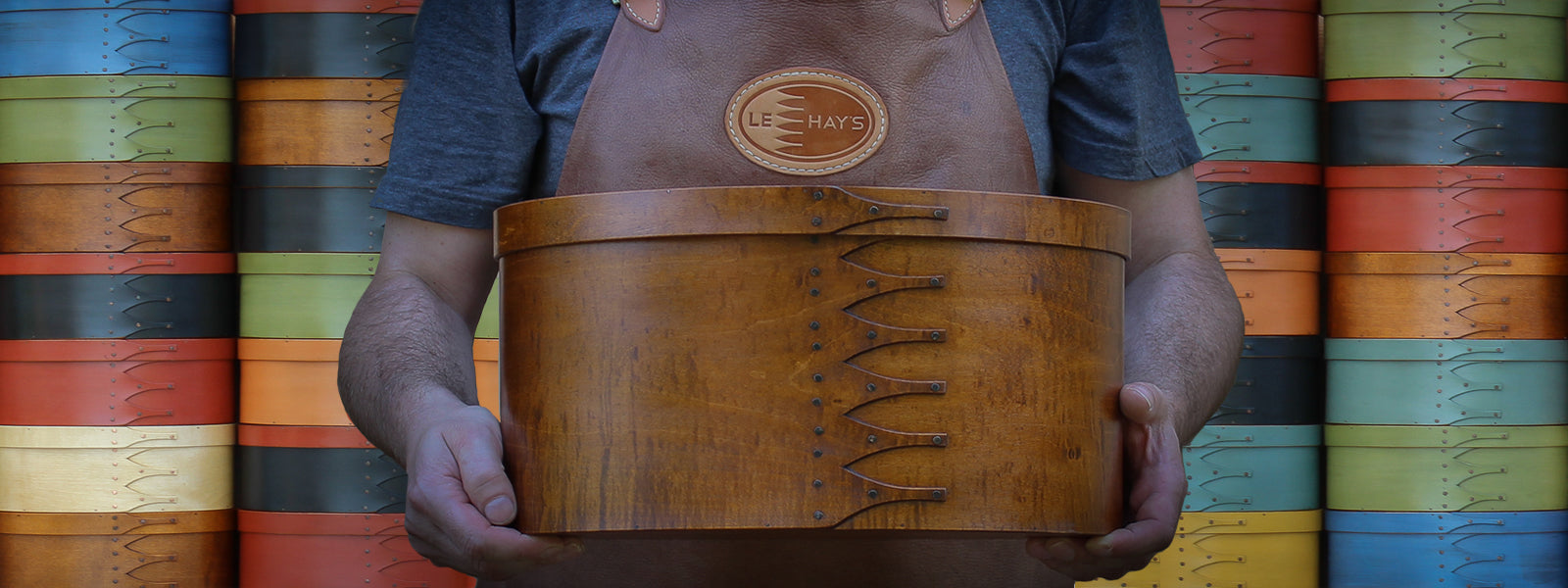 A size #8 tall shaker oval box being held by Robert LeHay standing in front of numerous size #5 shaker boxes